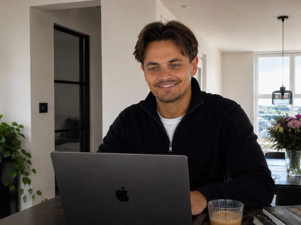 Lucas Ilcken smiling behind his laptop at home